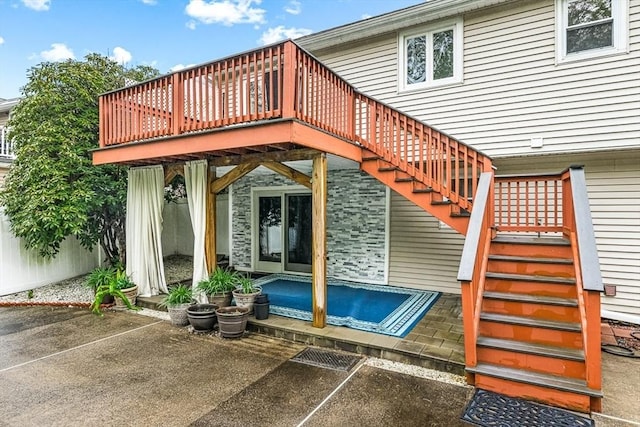 view of exterior entry featuring a patio area, a wooden deck, and uncovered parking
