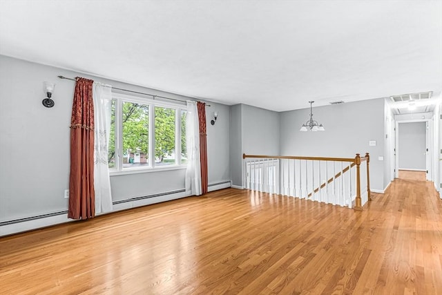 empty room with light wood finished floors, a chandelier, a baseboard heating unit, and baseboards