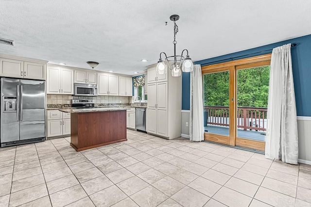 kitchen featuring stainless steel appliances, tasteful backsplash, a center island, hanging light fixtures, and baseboards