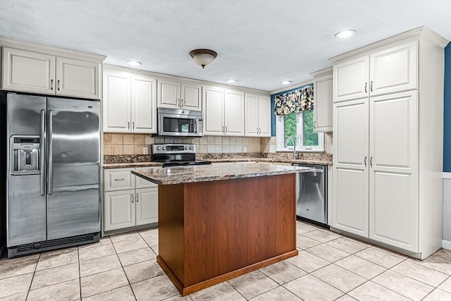 kitchen with stainless steel appliances, decorative backsplash, dark stone countertops, a kitchen island, and recessed lighting