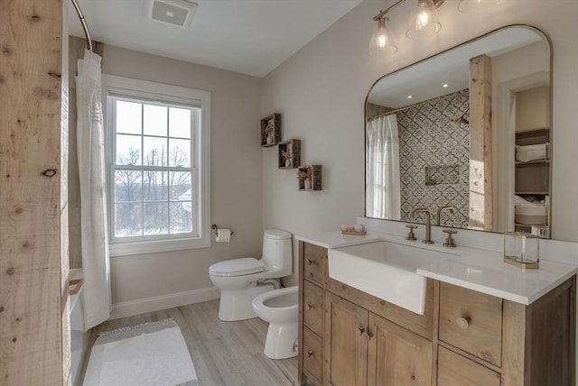 full bathroom featuring hardwood / wood-style floors, vanity, toilet, a bidet, and shower / bath combo with shower curtain