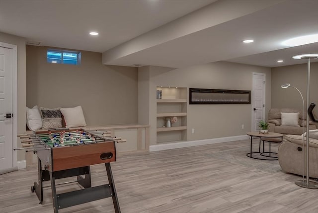 recreation room with built in features and light hardwood / wood-style flooring