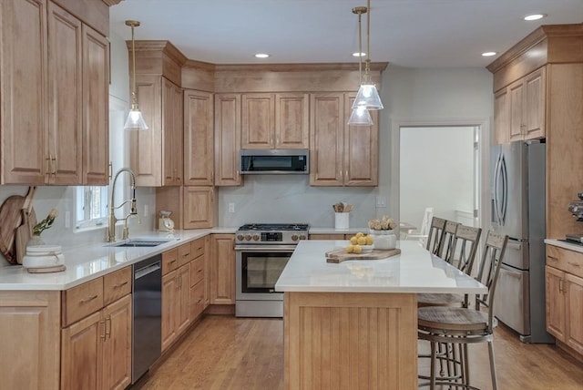 kitchen with a breakfast bar, sink, a center island, pendant lighting, and stainless steel appliances