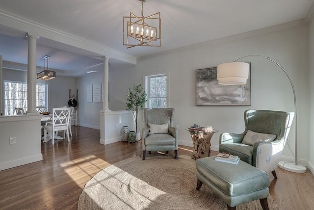 sitting room featuring crown molding, dark hardwood / wood-style floors, decorative columns, and a notable chandelier