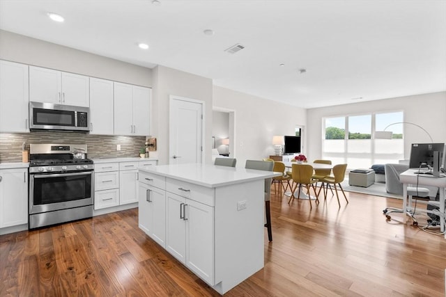 kitchen with white cabinetry, appliances with stainless steel finishes, a center island, and a breakfast bar area