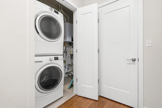 washroom with light wood-type flooring, water heater, and stacked washer / dryer