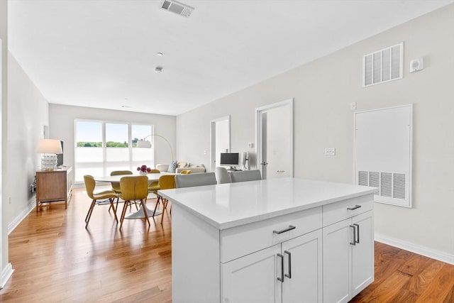 kitchen with white cabinetry, light hardwood / wood-style flooring, and a center island