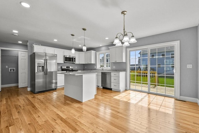 218 Tuttle St, Fall River, MA 02724 - kitchen featuring appliances with stainless steel finishes, light wood-type flooring, a chandelier, white cabinetry, and a kitchen island
