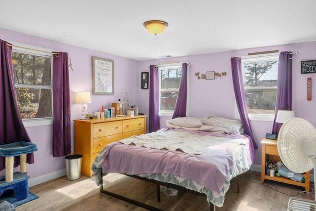 bedroom featuring light wood finished floors, multiple windows, and baseboards