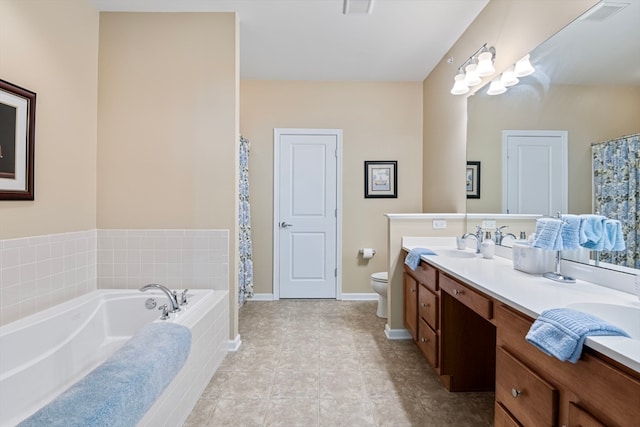 bathroom with tile patterned flooring, a relaxing tiled tub, toilet, and vanity