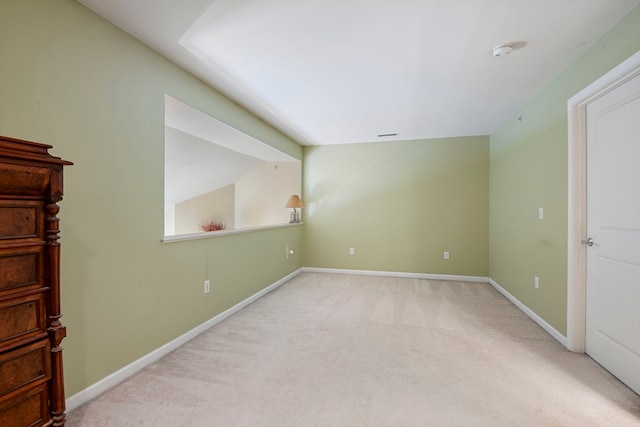 spare room featuring light colored carpet and lofted ceiling