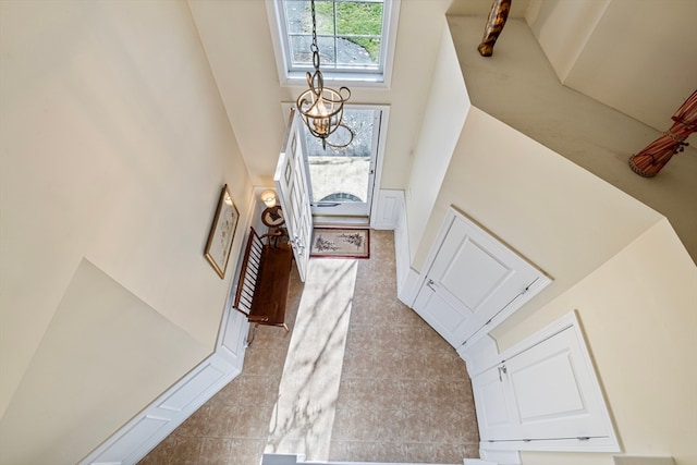 entryway with light tile patterned flooring, a high ceiling, and an inviting chandelier