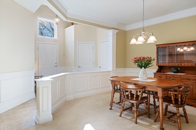 carpeted dining area featuring a chandelier, decorative columns, and crown molding