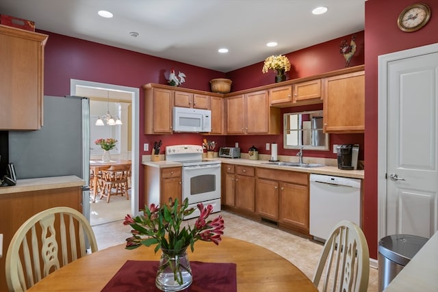 kitchen with white appliances, sink, pendant lighting, light tile patterned floors, and a chandelier