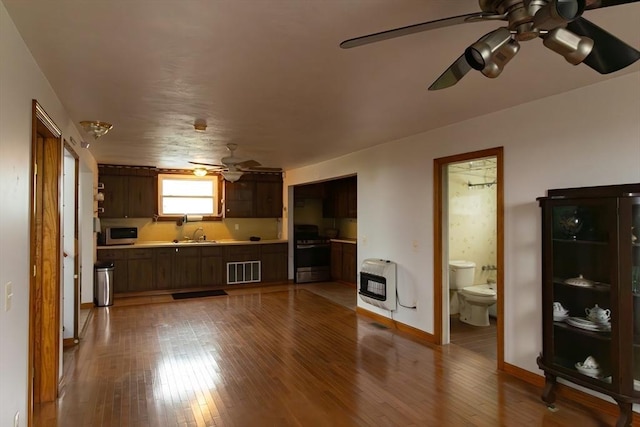 living room with hardwood / wood-style floors, heating unit, ceiling fan, and sink