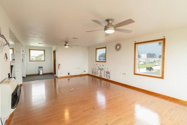 unfurnished living room featuring hardwood / wood-style floors, heating unit, and ceiling fan