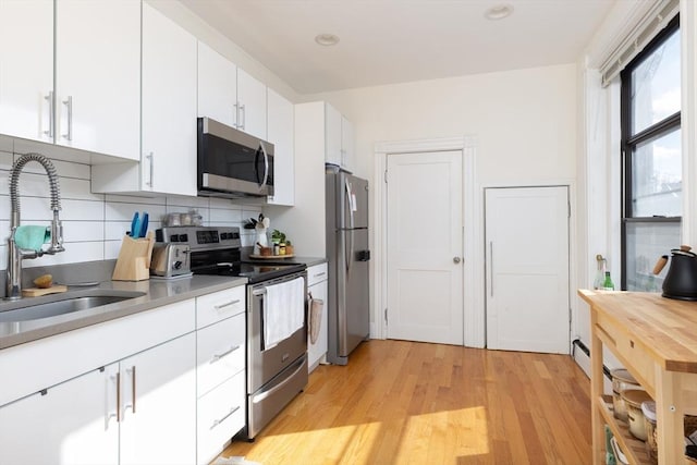 499 Beacon St, Boston, MA 02215 - kitchen featuring appliances with stainless steel finishes, a sink, decorative backsplash, white cabinets, and light wood-style flooring