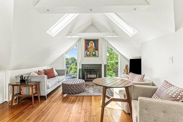 living room with a skylight, light wood finished floors, lofted ceiling, and a fireplace