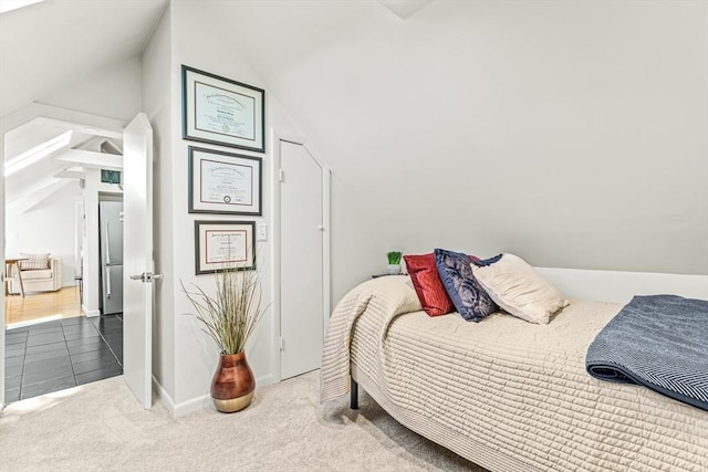 bedroom with lofted ceiling, carpet, and stainless steel refrigerator