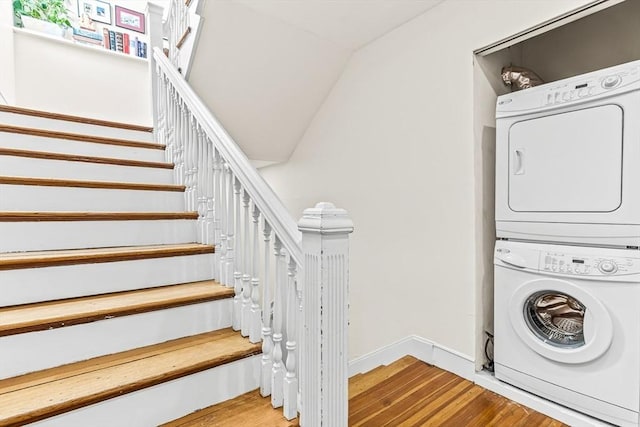 laundry room with estacked washer and dryer, wood finished floors, and baseboards