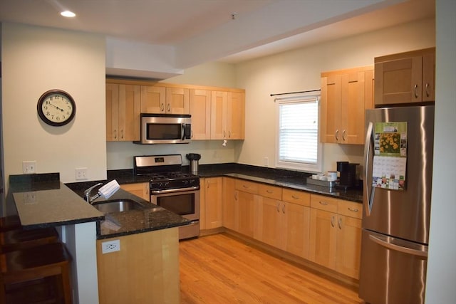 23 Beech St Unit 2, Framingham, MA 01702 - kitchen with stainless steel appliances, a peninsula, light brown cabinetry, dark stone countertops, and light wood-style floors