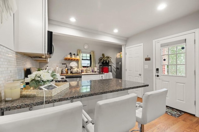 99 Lincoln St, Stoughton, MA 02072 - kitchen with a peninsula, appliances with stainless steel finishes, light wood-type flooring, backsplash, and white cabinets