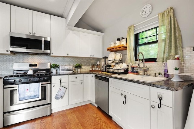 99 Lincoln St, Stoughton, MA 02072 - kitchen with appliances with stainless steel finishes, a sink, vaulted ceiling, decorative backsplash, and light wood-style flooring