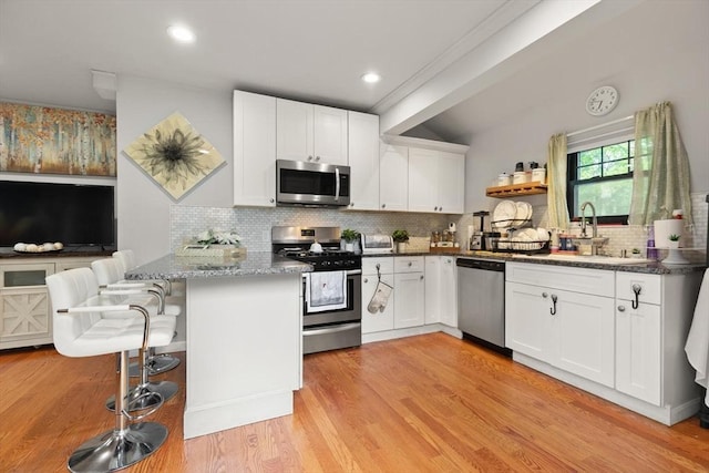 99 Lincoln St, Stoughton, MA 02072 - kitchen featuring appliances with stainless steel finishes, a sink, tasteful backsplash, white cabinetry, and light wood-style flooring