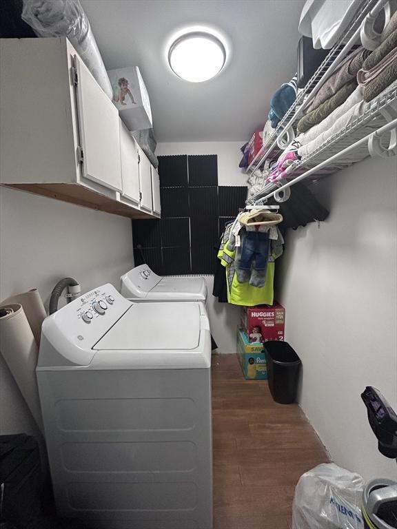 laundry room with dark wood-type flooring, washing machine and dryer, and cabinets