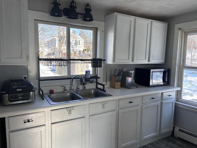 kitchen with white cabinetry, sink, a baseboard radiator, and plenty of natural light