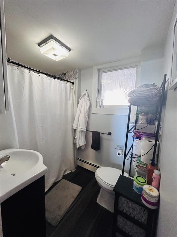 bathroom featuring vanity, a baseboard heating unit, hardwood / wood-style flooring, and toilet