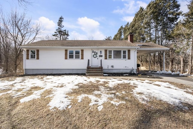 view of front of property featuring driveway, a chimney, and a carport