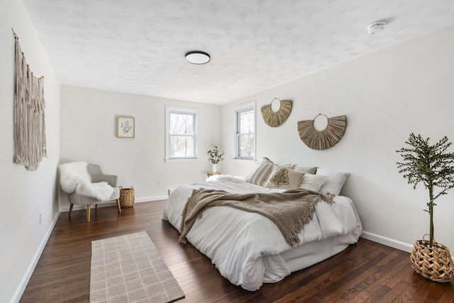 bedroom with dark wood-style floors, a textured ceiling, and baseboards