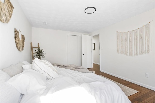 bedroom with dark wood-style flooring, a closet, and baseboards