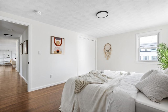 bedroom featuring a closet, baseboards, and dark wood-style flooring