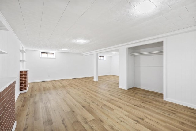 basement featuring light wood finished floors and baseboards