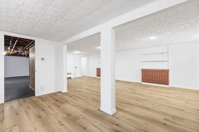 finished basement featuring light wood-style floors, radiator, and baseboards