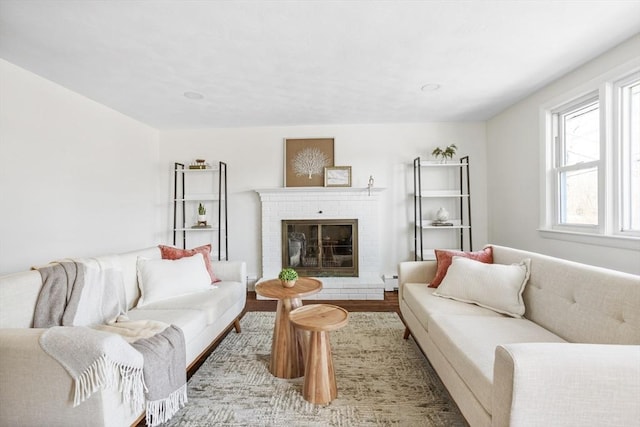 living room featuring a baseboard heating unit, a brick fireplace, and wood finished floors