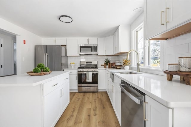 kitchen featuring light countertops, appliances with stainless steel finishes, a sink, and white cabinets