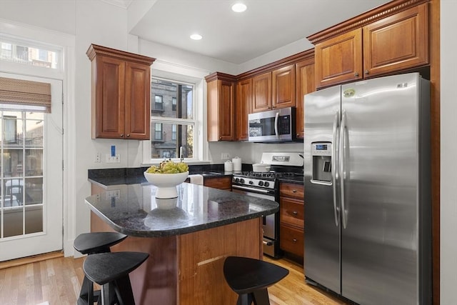 kitchen with plenty of natural light, a kitchen island, stainless steel appliances, and light hardwood / wood-style flooring