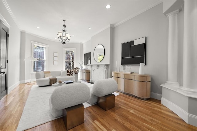 living room featuring decorative columns, an inviting chandelier, light hardwood / wood-style floors, and ornamental molding