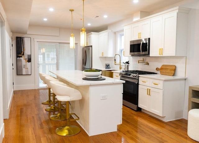 567 Park St Unit 1And B, Boston, MA 02124 - kitchen featuring appliances with stainless steel finishes, a center island, a breakfast bar area, decorative backsplash, and white cabinets