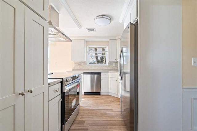 kitchen with white cabinetry, stainless steel appliances, light hardwood / wood-style floors, and wall chimney exhaust hood