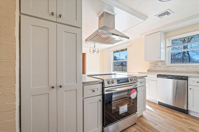 kitchen with white cabinetry, tasteful backsplash, island range hood, appliances with stainless steel finishes, and light hardwood / wood-style floors