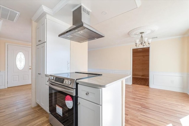 kitchen featuring crown molding, stainless steel electric range, white cabinets, and island exhaust hood