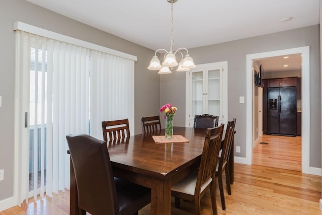 dining space with light wood-type flooring and an inviting chandelier