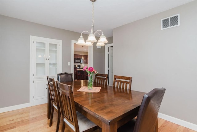 dining area featuring light hardwood / wood-style flooring and a notable chandelier