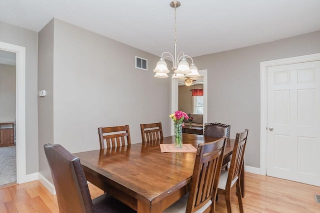 dining space with light hardwood / wood-style flooring and a notable chandelier