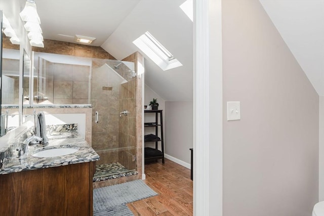 bathroom featuring wood-type flooring, an enclosed shower, vanity, and lofted ceiling with skylight