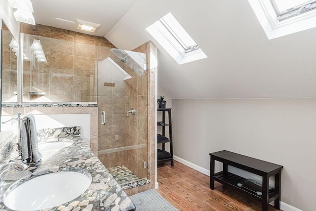 bathroom featuring sink, vaulted ceiling with skylight, wood-type flooring, and a shower with shower door